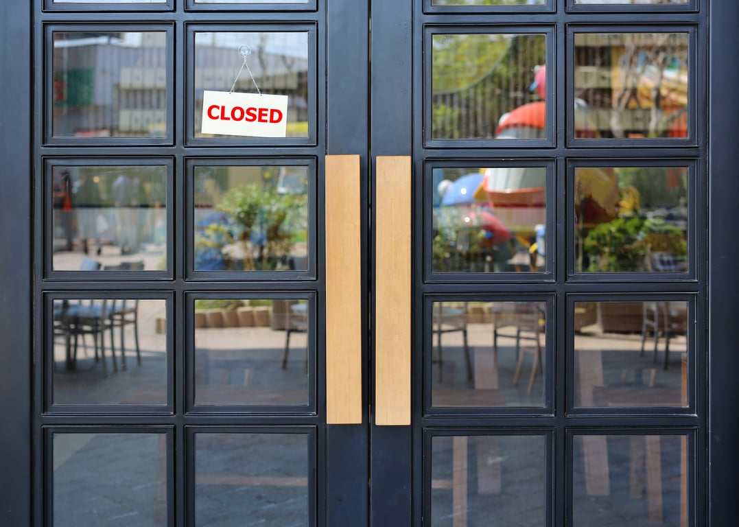 Closed sign hanging on hotel door, reflecting outdoor scenery