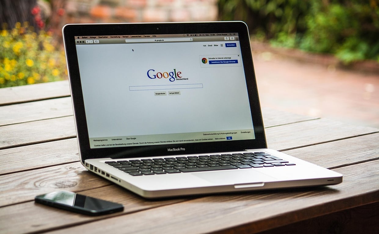A picture of a Macbook Pro and a phone placed on a table, with Google opened as a tab.